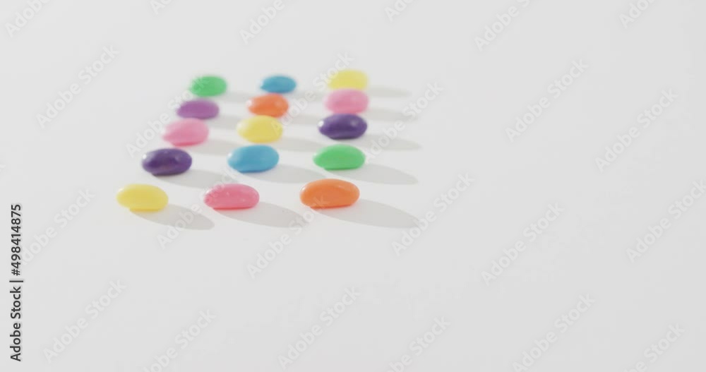 Video of overhead view of rows of multi coloured sweets with copy space over white background Video of overhead view of rows of multi coloured sweets with copy space over white background