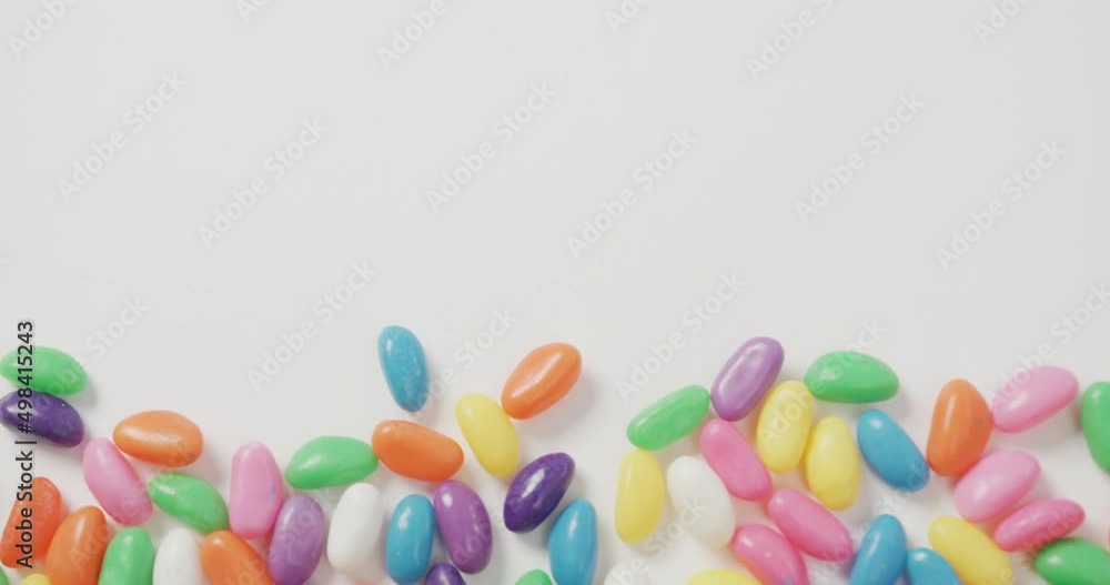 Video of overhead view of multi coloured sweets with copy space over white background Video of overhead view of multi coloured sweets with copy space over white background