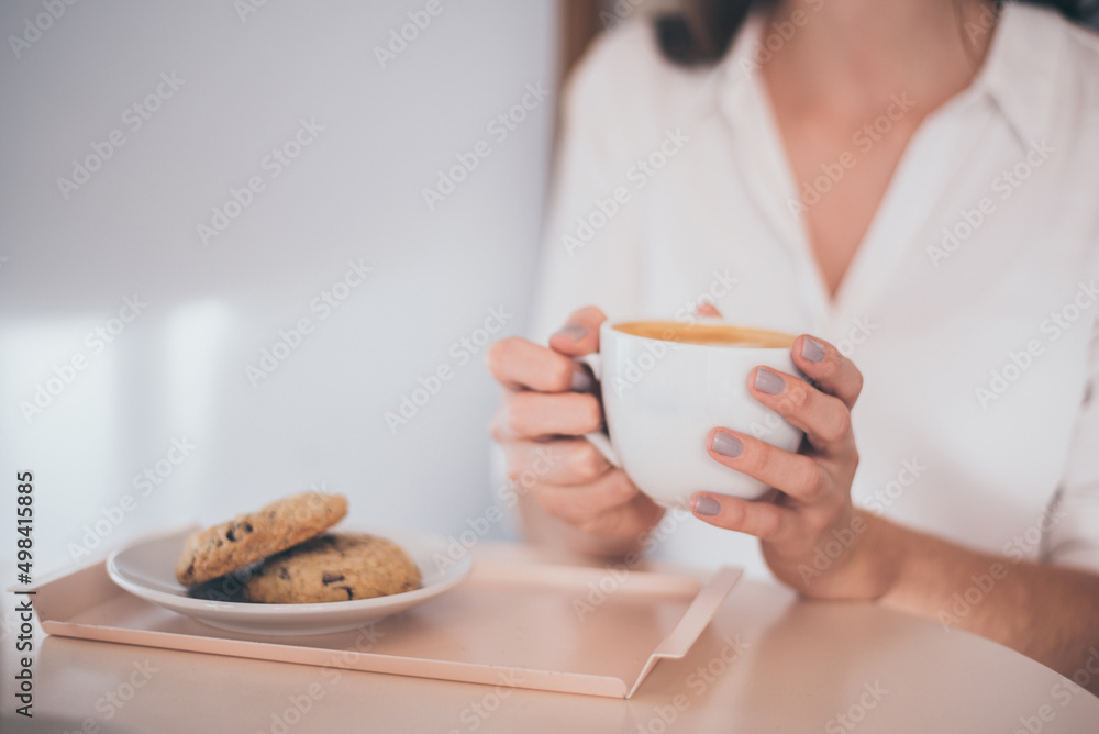 Woman having breakfast holding a cup of coffee and cookies Woman having breakfast holding a cup of coffee and cookies