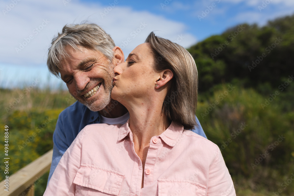 Caucasian mature woman kissing happy man with eyes closed Caucasian mature woman kissing happy man with eyes closed