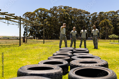 Male instructor instructing group of male and female soldiers for tires obstacle course at boot camp