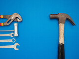 Work tools on a blue background. A hammer, screwdriver, spanner, and pliers