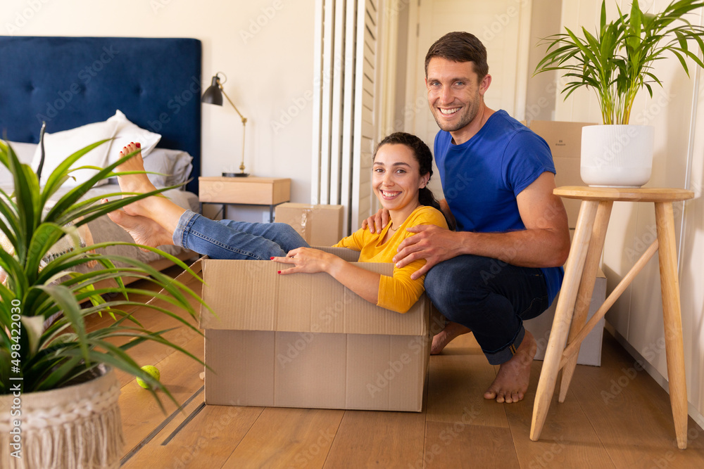 Portrait of caucasian couple smiling and sitting in the cardboard box at home Portrait of caucasian couple smiling and sitting in the cardboard box at home