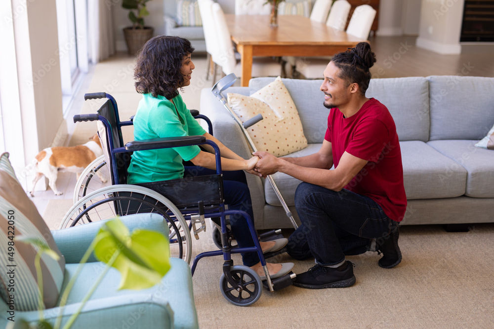 African american man holding hands disabled wife sitting on the wheelchair at home African american man holding hands disabled wife sitting on the wheelchair at home