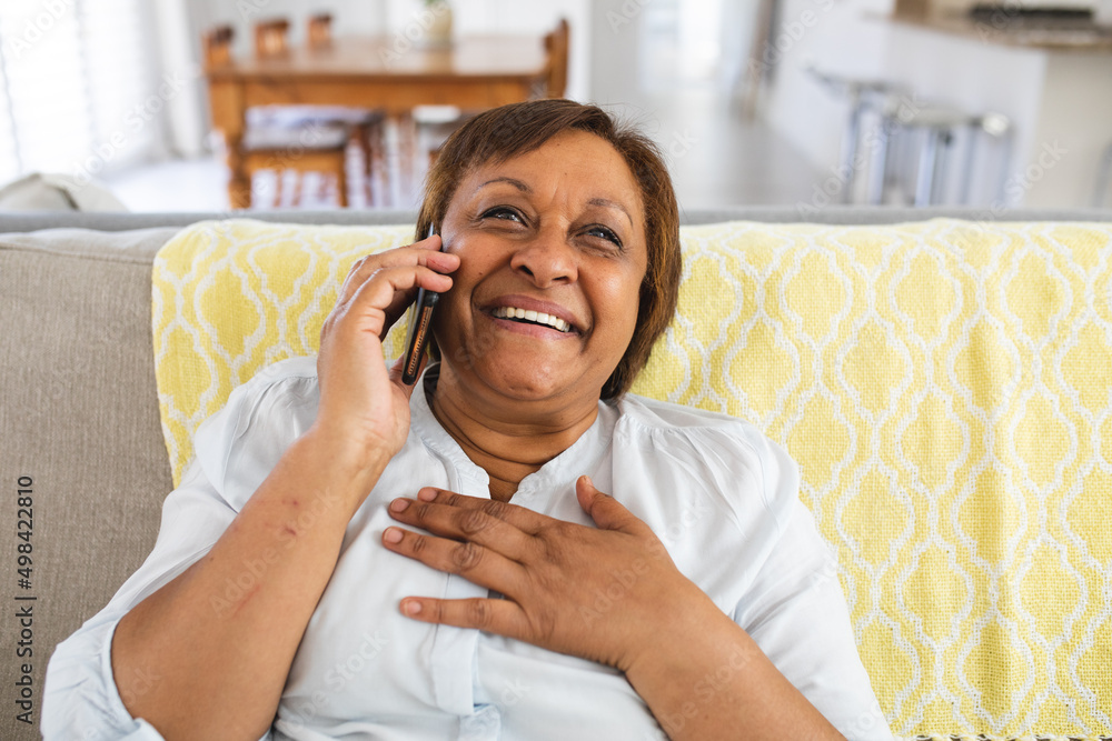 Smiling senior woman talking on smart phone while sitting on sofa at home Smiling senior woman talking on smart phone while sitting on sofa at home
