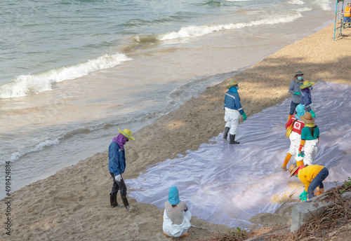 Rayong, Thailand - February 1, 2022: Volunteers cleaning sea shore from the oil spill incidents in Rayong beach. photo