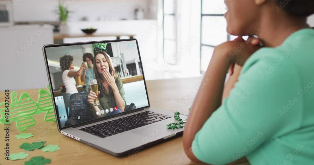 Smiling caucasian woman with beer wearing clover shape band on video call on laptop Smiling caucasian woman with beer wearing clover shape band on video call on laptop