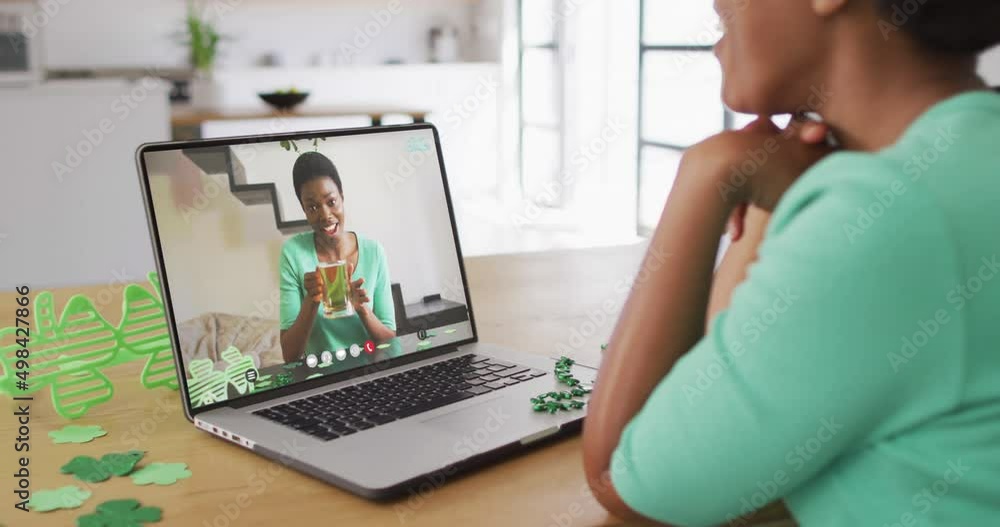 Smiling african american woman with beer wearing clover shape band on video call on laptop Smiling african american woman with beer wearing clover shape band on video call on laptop
