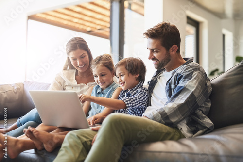 Connected online and as a family. Shot of a mother and father using a laptop with their son and daughter on the sofa at home.