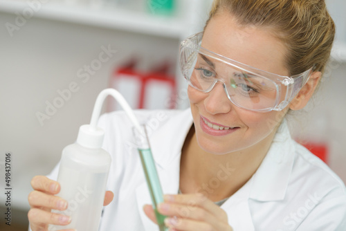 Foto positive minded woman smiling while looking at a test tube