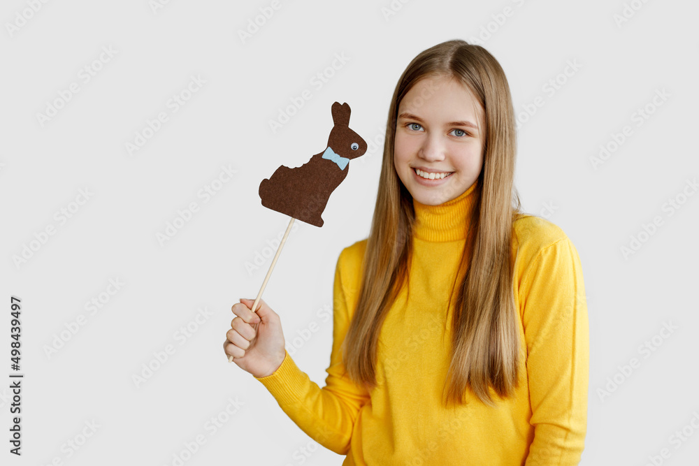 A teenage girl holds a brown felt rabbit in her hands and smiles, a light background, a place for text. Happy Easter, Easter holiday, Easter card A teenage girl holds a brown felt rabbit in her hands and smiles, a light background, a place for text. Happy Easter, Easter holiday, Easter card