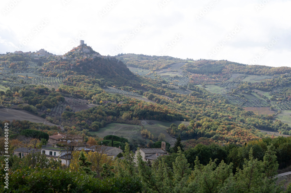 Hiking on hills near Bagno Vignoni and view on Rocco Tuscany, Italy. Tuscan landscape with cypress trees, vineyards, forests and ploughed fields in autumn.