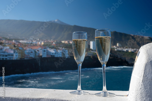 New year celebration with two glasses of champagne or Spanish cava sparkling wine and view on Teide, black lava coast, blue Atlantic ocean, Canary islands, winter tourists destination