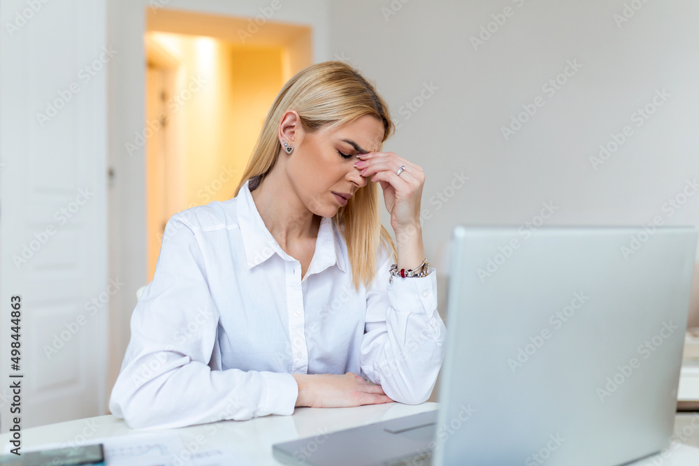 Young frustrated woman working at office desk in front of laptop suffering from chronic daily headaches, treatment online, appointing to a medical consultation, electromagnetic radiation, sick pay Young frustrated woman working at office desk in front of laptop suffering from chronic daily headaches, treatment online, appointing to a medical consultation, electromagnetic radiation, sick pay