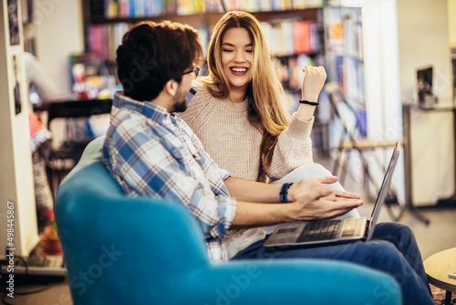 Attractive man in eyeglasses and charming woman using laptop resting at cafe with cup of coffee.