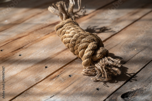 Coiling a natural rope against a wooden background. Rough, cracked boards. Natural lighting.