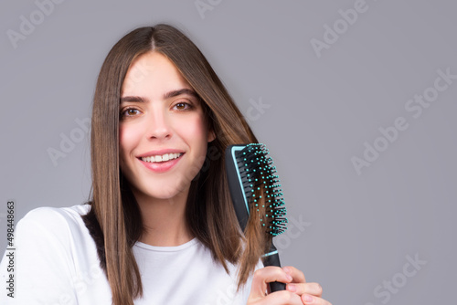 Close up portrait of happy beautiful girl with shiny hair with comb.