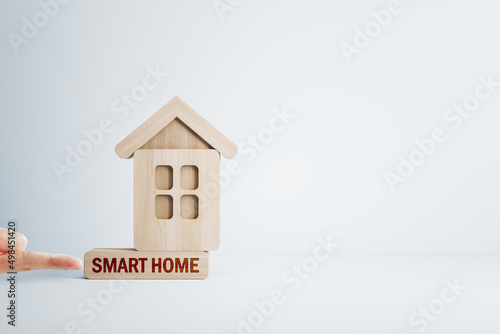 Finger pushing abstract wooden house on white mortgage backdrop with mock up place. Smart home, oan, bank and money concept. photo