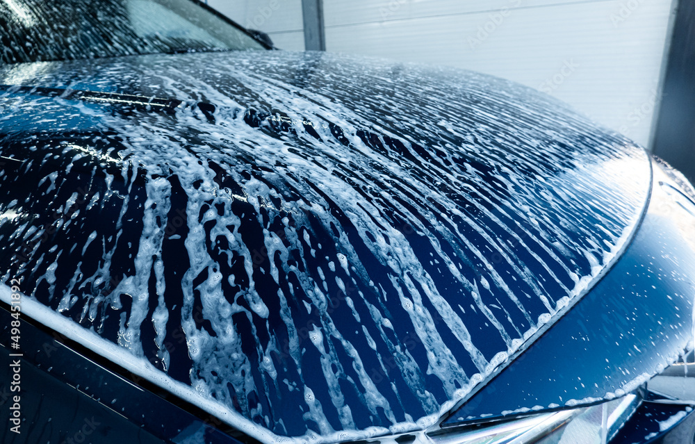 Selfservice car wash station. Active foam is cleaning a dirty sedan