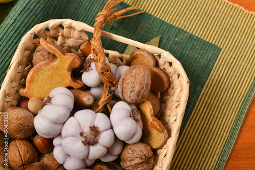 wicker basket with nuts, garlic and cookie on a green fabric, still life and decorations, red wooden background