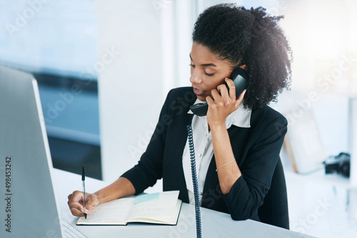 Im calling to confirm our meeting for tomorrow.... Shot of a young businesswoman talking on a telephone in an office.