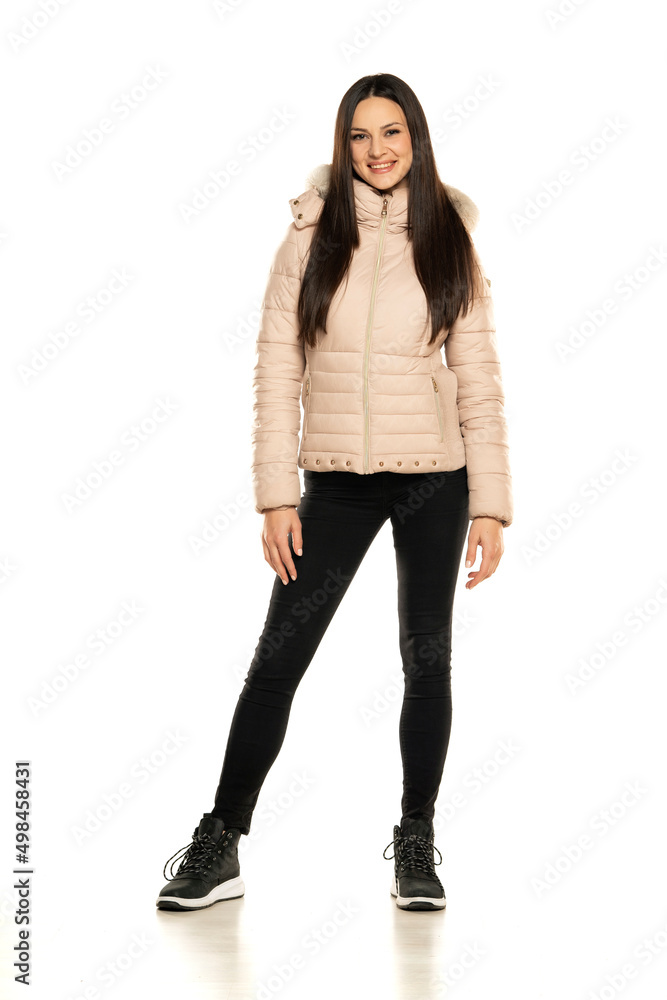 Front view of a young woman in winter jacket, and black jeans posing on a white background Front view of a young woman in winter jacket, and black jeans posing on a white background