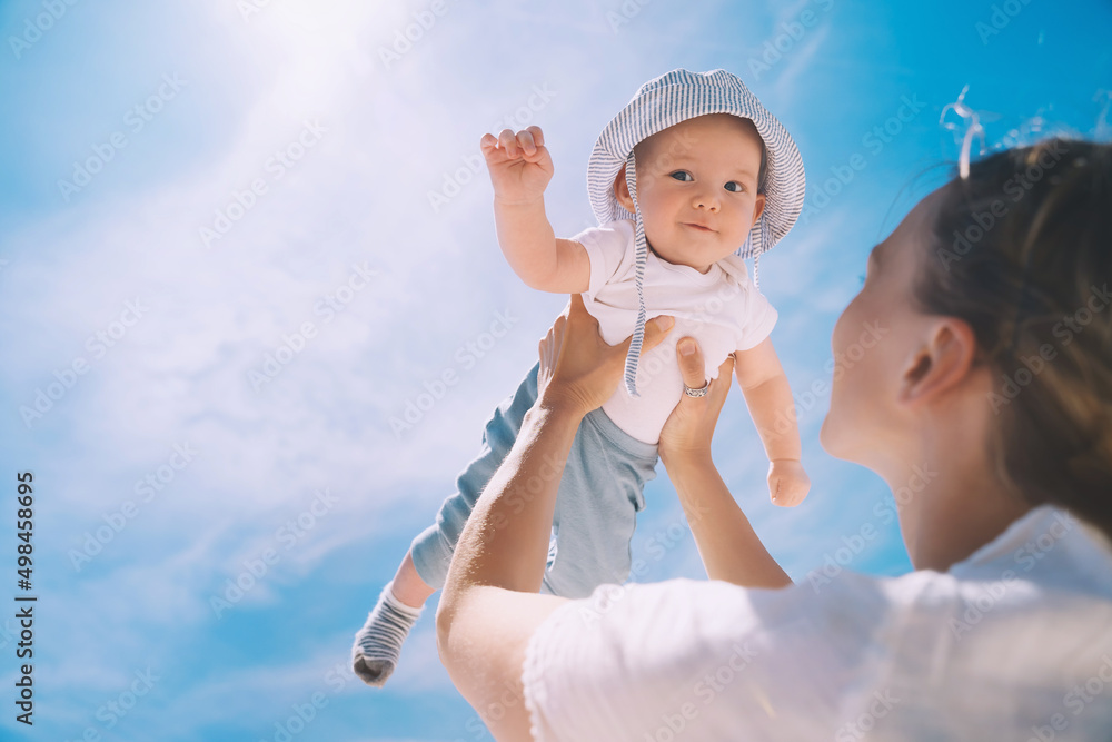 Mother throwing baby up against the blue sky. Happy family outdoors