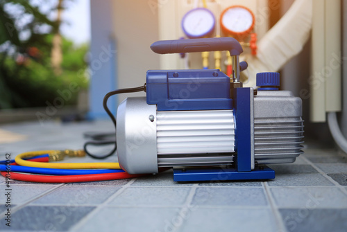 Canvas Print The vacuum unit is placed beside the outdoor air conditioner unit and manifold gauge for use in servicing the air conditioner in the summer