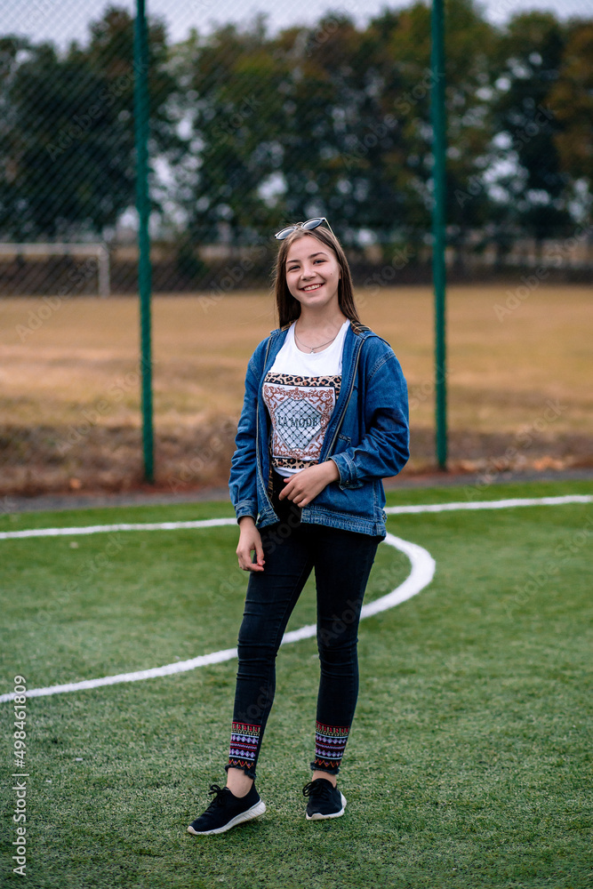 Portrait of a girl in jeans on a football field
