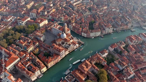 Beautiful aerial view of San Geremia Church and Grand Canal located in the sestiere of Cannaregio district in Venice, Italy. Flying over of medieval romantic city looking down to boats at sunset in 4K