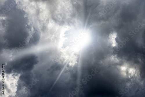 Close-up of a dark dramatic cloudy sky with sunbeams, backlit, full frame, photography. 