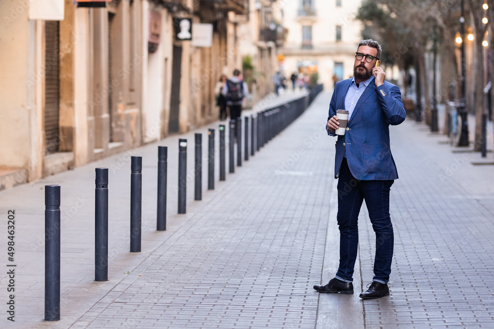 Well-dressed man standing on downtown talking on phone holding coffee cup