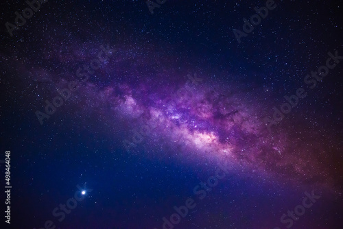 Milky way in the night sky and stars on dark background with noise and grain. Photo taken with long exposure and white balance selected. 