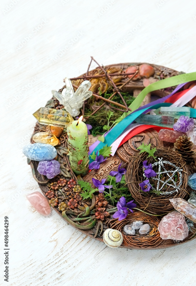 Wiccan altar for Beltane sabbath. spring pagan festive ritual. wheel of the year, colorful ribbons, gemstones, flowers, pentagram amulet, candle - symbol of Beltane celtic holiday, spring season.
