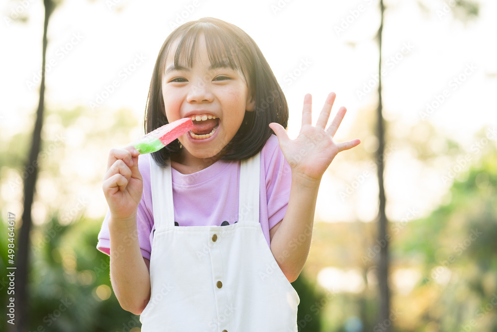 Image of Asian little girl eating ice cream at park Image of Asian little girl eating ice cream at park