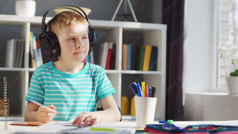 Boy is Doing his Homework at the Table. Cute Child is Learning at Home with the Help of Textbooks and School Materials. Study and Education Concept. Boy is Doing his Homework at the Table. Cute Child is Learning at Home with the Help of Textbooks and School Materials. Study and Education Concept.