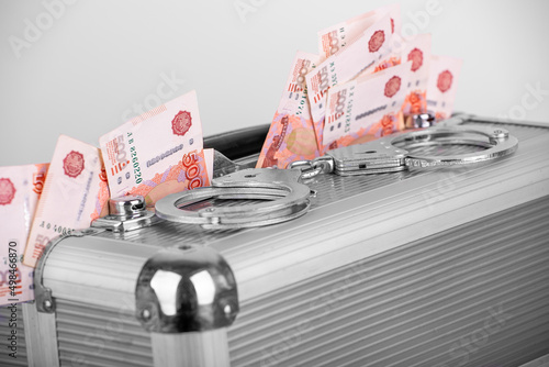 Handcuffs lying on a briefcase with money sticking out of it