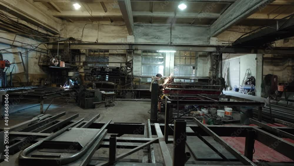 A welder and a metal cutter in the workshop of a metalworking workshop prepares steel parts. Sparks.Workers work at the factory, the welder prepares, the workflow in the shop A welder and a metal cutter in the workshop of a metalworking workshop prepares steel parts. Sparks.Workers work at the factory, the welder prepares, the workflow in the shop