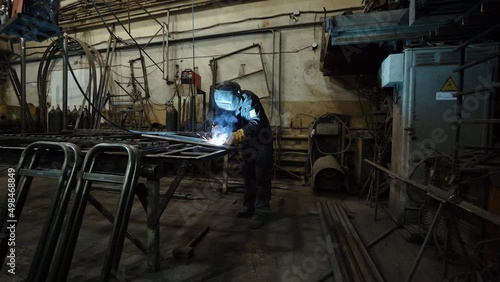 A worker cooks metal on a welding machine in production. a worker with a welding machine to cook parts