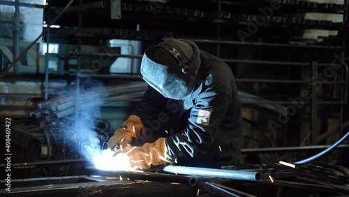 A worker cooks metal on a welding machine in production. a worker with a welding machine to cook parts