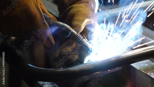 A worker cooks metal on a welding machine in production. a worker with a welding machine to cook parts. Close up