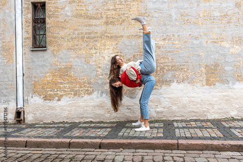 funny teenager carrying her best friend piggyback on the street at the old wall, positive emotions photo