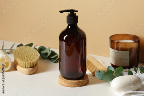 Amber glass shampoo bottle and bathroom accessories on table on beige background. SPA natural organic beauty product design.