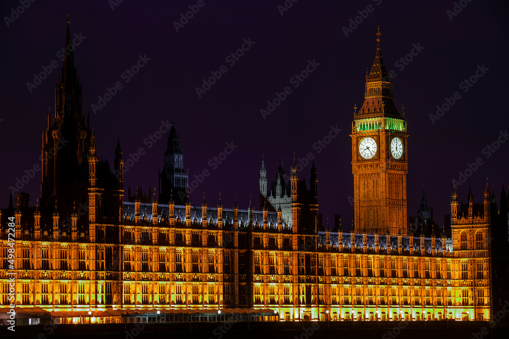 Big Ben of the Houses of Parliament London England UK at night striking midnight on new year's eve which is a popular travel destination tourist attraction landmark of the city centre, stock photo