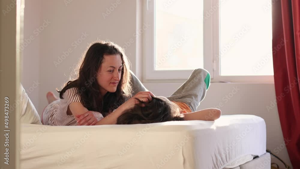 Mother strokes her son on the head, the boy with his mother lies on the bed, the child spends the morning with his mother, the woman touches the child's hair, mother's day Mother strokes her son on the head, the boy with his mother lies on the bed, the child spends the morning with his mother, the woman touches the child's hair, mother's day