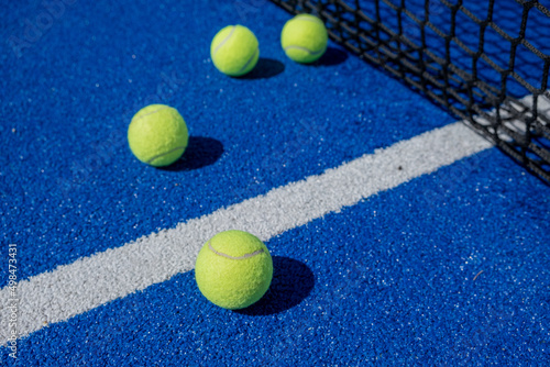 selective focus, four paddle tennis balls on a blue paddle tennis court close to the net © Vic