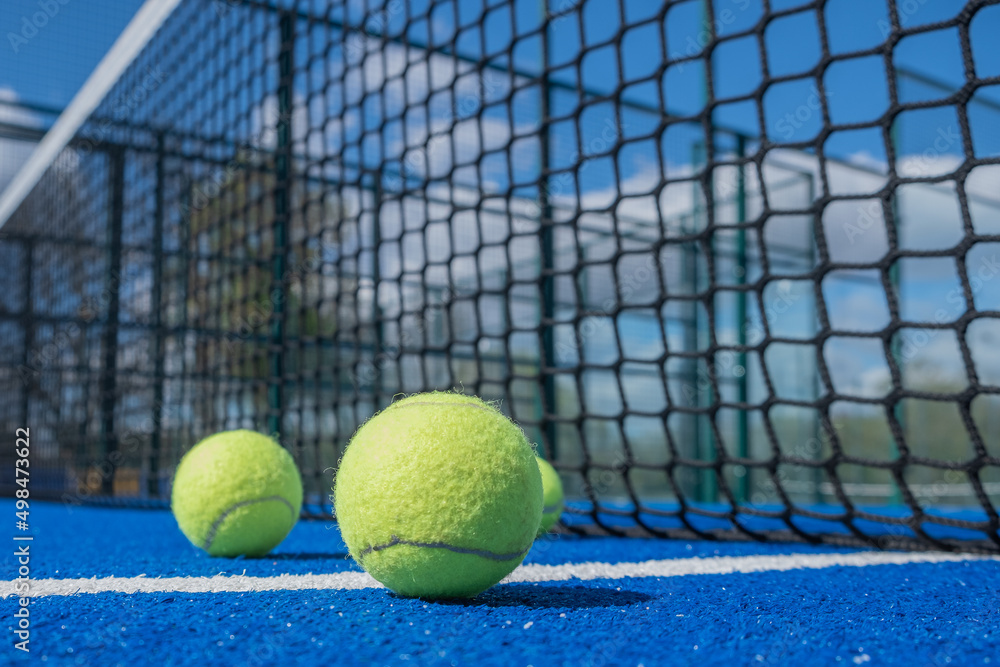 selective focus, paddle tennis balls on a blue paddle tennis court close to the net, racket sports concept