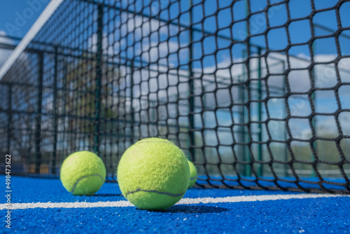 selective focus, paddle tennis balls on a blue paddle tennis court close to the net, racket sports concept © Vic