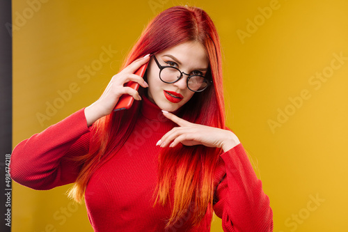 Glamour woman wearing glasses using smartphone on yellow background