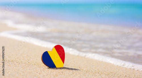 Flag of Romania in the shape of a heart on a sandy beach. The concept of the best vacation in Romania resorts.